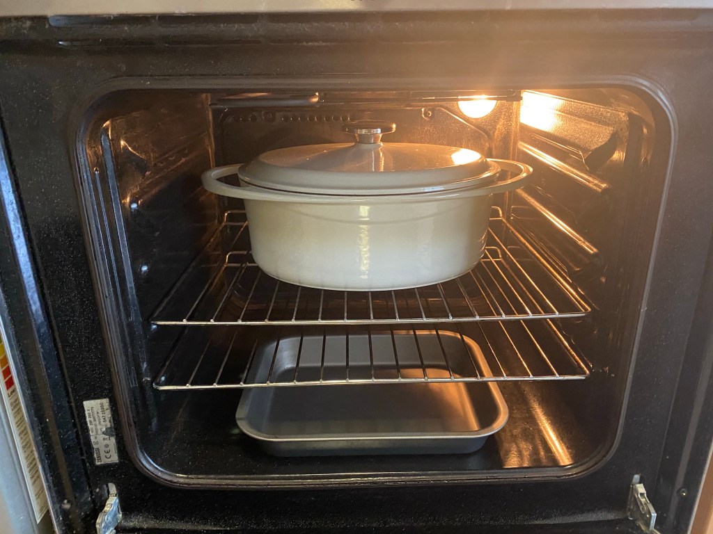 An oven with a dutch oven and baking sheet inside.