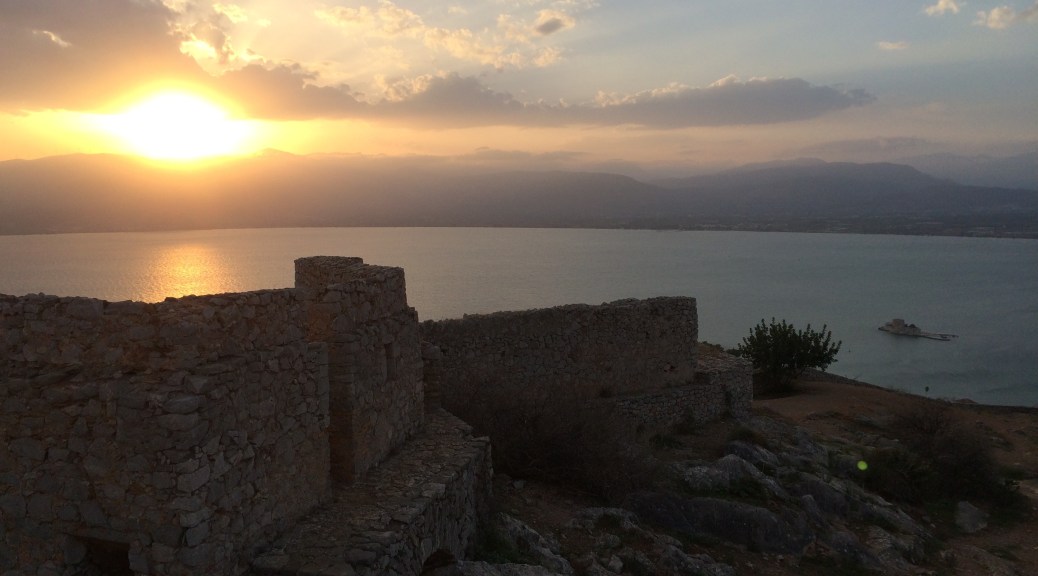 A sunset view over a sandstone fortress, to the open sea beyond and a sky swept with clouds.
